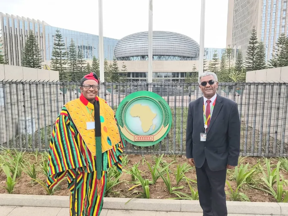 Dos delegados junto al emblema de la Unión Africana frente a su sede.